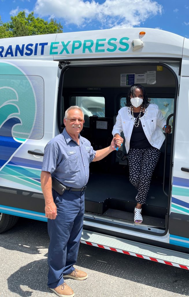 Driver helping woman step down from bus