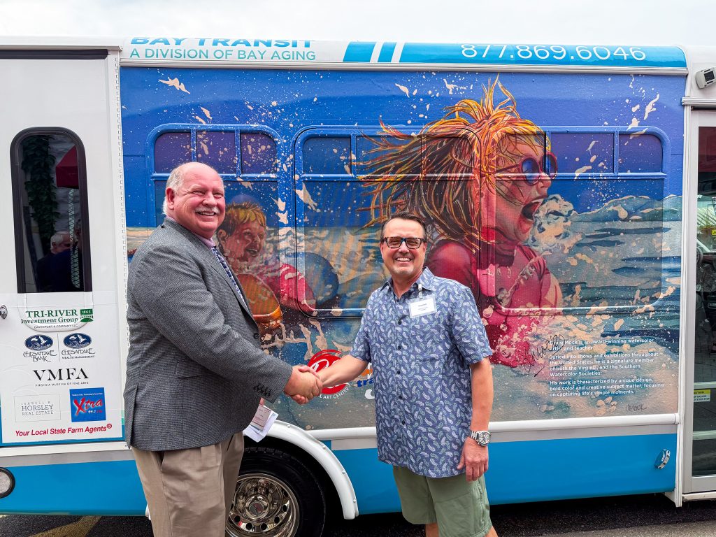 Two men shaking hands in front of bus