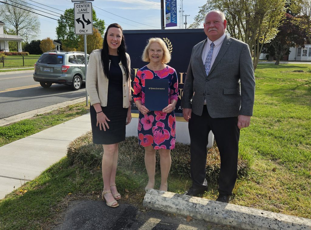 Three people standing in front of sign