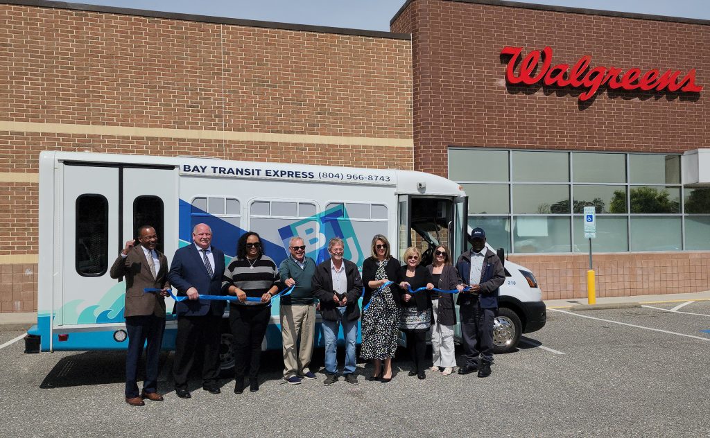 Group of people at ribbon cutting ceremony in front of bus
